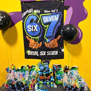 May include: A black birthday banner with blue and green graffiti-style text reading Jahmari was six now he's seven, featuring illustrations of hands and the text Bruh, six seven. Below is a tiered cake, party favor bags, and stacks of plates.
