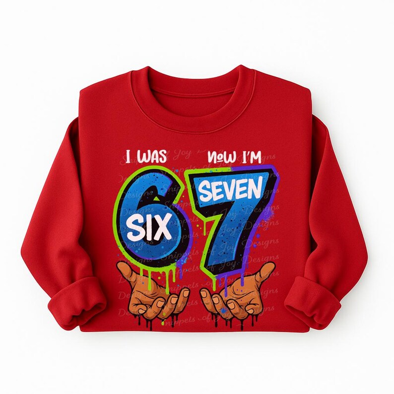 May include: A red long-sleeved sweatshirt with the text "I WAS SIX NOW I'M SEVEN". The number "6" is in a blue circle, and the number "7" is in blue. The design includes two hands with dripping paint.