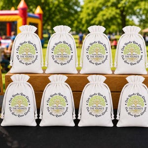 May include: White drawstring favor bags with a tree design and the text "Our Roots Run Deep, The Young's, Love Grows Deeper." Two small chalkboards display text: "Good Food, Good People, Good Times" and "Together is our favorite place to be."