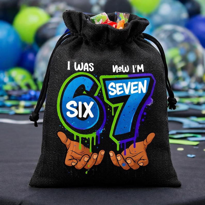 May include: A black drawstring gift bag featuring a graphic print with the text I WAS SIX NOW I'M SEVEN. The design includes large blue numbers 6 and 7 with green and purple outlines, and two open hands reaching upward from the bottom of the bag.