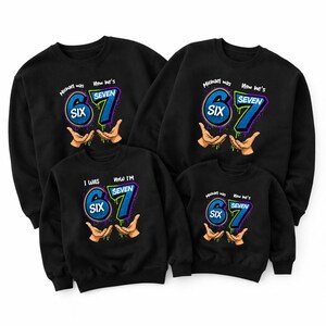 May include: Black sweatshirts with a birthday theme. Each sweatshirt features the text "Michael was SIX, Now he's SEVEN" or "I WAS SIX, Now I'M SEVEN" in blue and green, with hands holding the numbers.