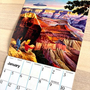 May include: A calendar featuring a vintage illustration of a canyon landscape with a UFO. The calendar page shows the month of January with dates and days of the week. Two people are sitting on a cliff, looking at the canyon. The image has a retro, travel-themed aesthetic.