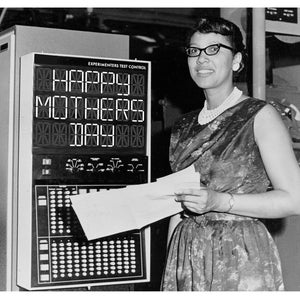 May include: A black and white photo of a woman standing in front of a computer with a digital display that reads "HAPPY MOTHERS DAY".