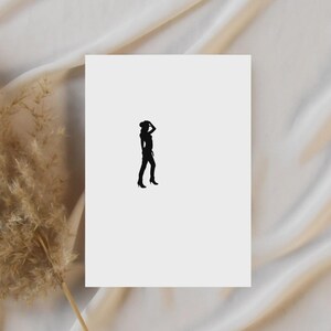 May include: A black silhouette of a person wearing a hat and heels, standing on a white background. The person is holding their hat with one hand. The background is a soft, off-white fabric.