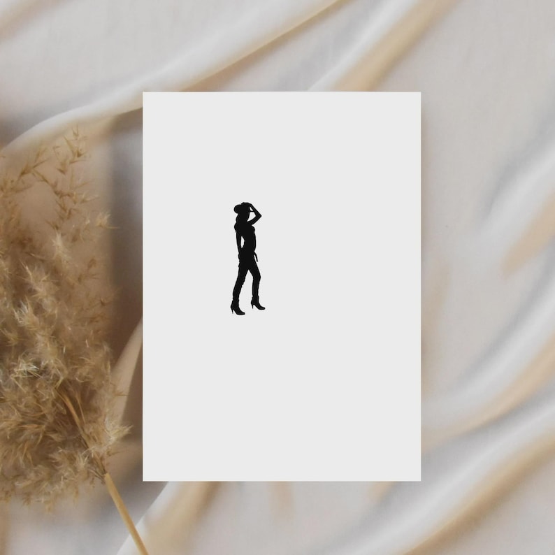 May include: A black silhouette of a person wearing a hat and heels, standing on a white background. The person is holding their hat with one hand. The background is a soft, off-white fabric.