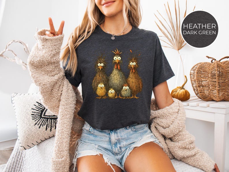 May include: Dark heather gray t-shirt featuring a whimsical illustration of a chicken family. The design includes six chickens with expressive eyes and detailed feathering. The shirt is a comfortable crew neck style.