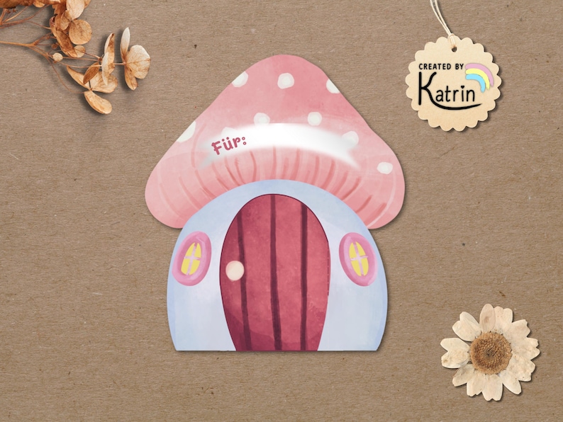 May include: A mushroom-shaped gift tag with a pink cap featuring white spots and a light blue base. The tag has a dark red door, two small yellow windows, and the word "F&uuml;r:" printed on the cap. A scalloped tag reads "CREATED BY Katrin".