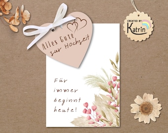 May include: A wedding card with a heart-shaped tag tied with a white ribbon. The tag reads "Alles Gute zur Hochzeit" and features two hearts. The card has floral and pampas grass accents. The text "Für immer beginnt heute!" is also visible.