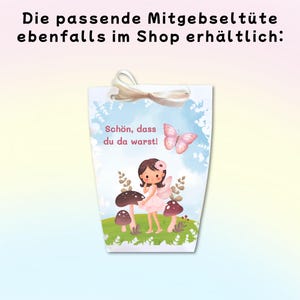 May include: A white paper gift bag with a ribbon handle featuring a cartoon illustration of a fairy standing among mushrooms, a pink butterfly, and the German text "Sch&ouml;n, dass du da warst!" with additional text above the bag.