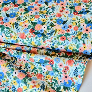 Puede incluir: Una tela azul claro con un patr&oacute;n floral. La tela presenta una variedad de flores en tonos de rosa, rojo, azul, amarillo y verde. Las flores est&aacute;n dispuestas en un patr&oacute;n aleatorio y est&aacute;n rodeadas de hojas y tallos.