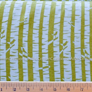May include: A white fabric with a repeating pattern of green vertical stripes and small white birds on branches. The fabric is measured with a ruler in inches.
