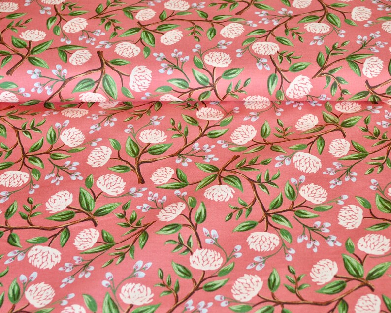 May include: Pink fabric with a white floral pattern. The flowers are stylized and resemble peonies. The fabric has a subtle texture.