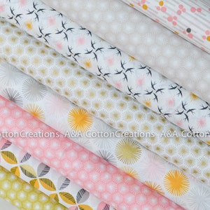 May include: A stack of eight fabric squares with different geometric patterns in shades of white, pink, yellow, and gray. The patterns include small circles, stars, and birds.