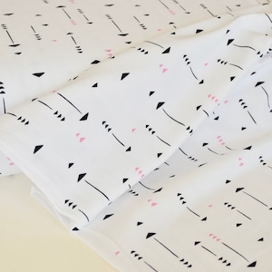 May include: White fabric with a repeating pattern of black arrows and pink triangles.
