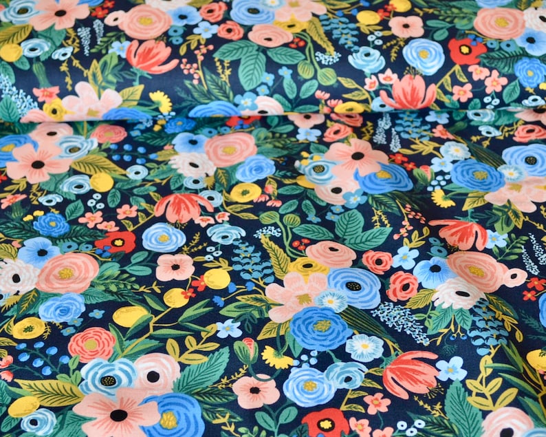 Puede incluir: Tela con un denso estampado floral sobre fondo azul marino. Presenta flores rosas, azules, amarillas y rojas, as&iacute; como hojas verdes. Las flores var&iacute;an en tama&ntilde;o y estilo.