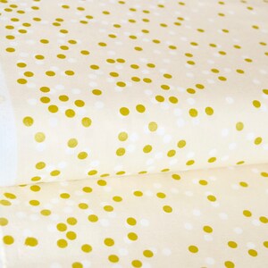 May include: Cream-colored fabric with a repeating pattern of small gold and white dots.