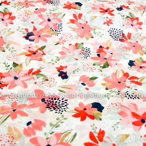 May include: White fabric with a pink and red floral print. The flowers are stylized and have a watercolor effect. The background is a light cream color.