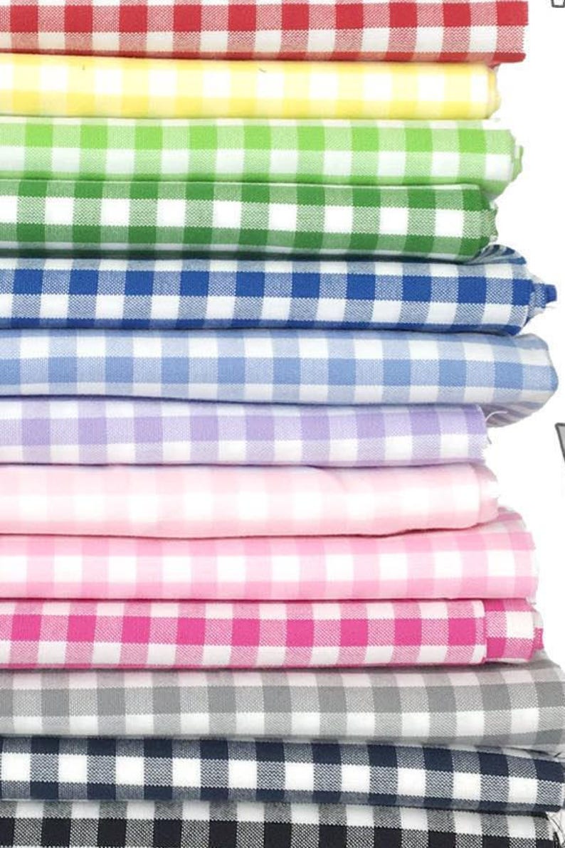 May include: A stack of 10 different colored gingham fabrics. The fabrics are folded and stacked on top of each other. The colors are red, yellow, green, blue, light blue, purple, pink, hot pink, gray, and black.