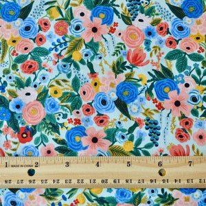 Puede incluir: Una tela azul claro con un patr&oacute;n floral con flores rosas, rojas, amarillas y azules. La tela se mide con una regla en pulgadas.