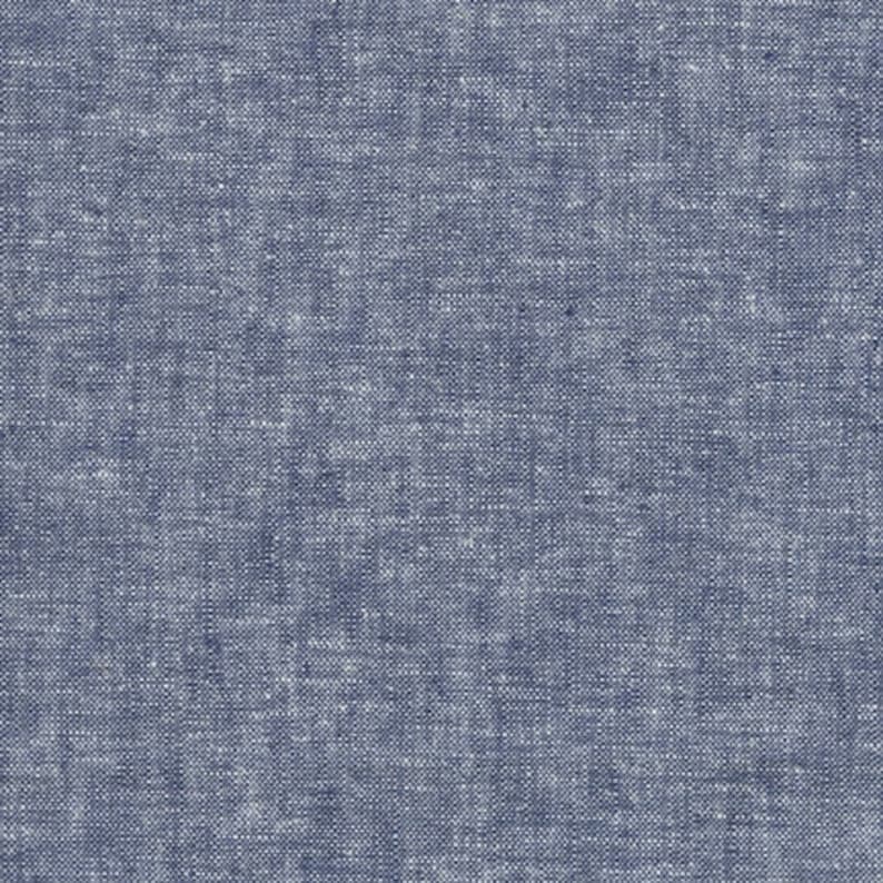 May include: Close-up of a textured fabric in a blue and white speckled pattern. The material has a woven appearance, with a mix of dark blue and lighter threads creating a mottled effect. The fabric appears to be a medium weight.