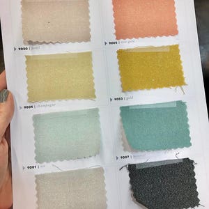 May include: Swatch card showing 10 different fabric colors from Cloud9 Fabrics. The colors are: pearl, rose gold, champagne, gold, ice, mineral, silver, graphite, and two more colors.