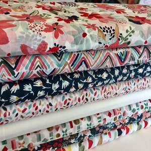 May include: A stack of six fabric rolls with different colorful patterns. The patterns include floral, geometric, and abstract designs. The fabrics are all white with various colors of pink, red, blue, green, and brown.