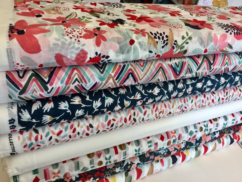 May include: A stack of six fabric rolls with different colorful patterns. The patterns include floral, geometric, and abstract designs. The fabrics are all white with various colors of pink, red, blue, green, and brown.