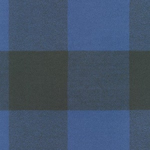 May include: A close-up of a fabric with a large blue and black plaid pattern. The squares are evenly sized and create a bold, graphic design. The fabric has a slightly textured appearance.