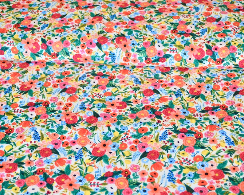 May include: Floral fabric with a white background, featuring a dense pattern of colorful flowers. The design includes red, pink, blue, and yellow blossoms with green foliage. The fabric is suitable for various sewing and crafting projects.