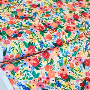 May include: Floral fabric with a white background and a colorful pattern of red, pink, blue, and yellow flowers. The fabric is from the Wildwood Collection.