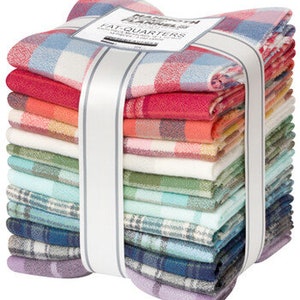 May include: A stack of colorful plaid fabric squares, bundled with a white ribbon. The fabric features a variety of colors, including red, blue, green, and purple. A label on top reads "Mammoth Flannel Fat Quarters".