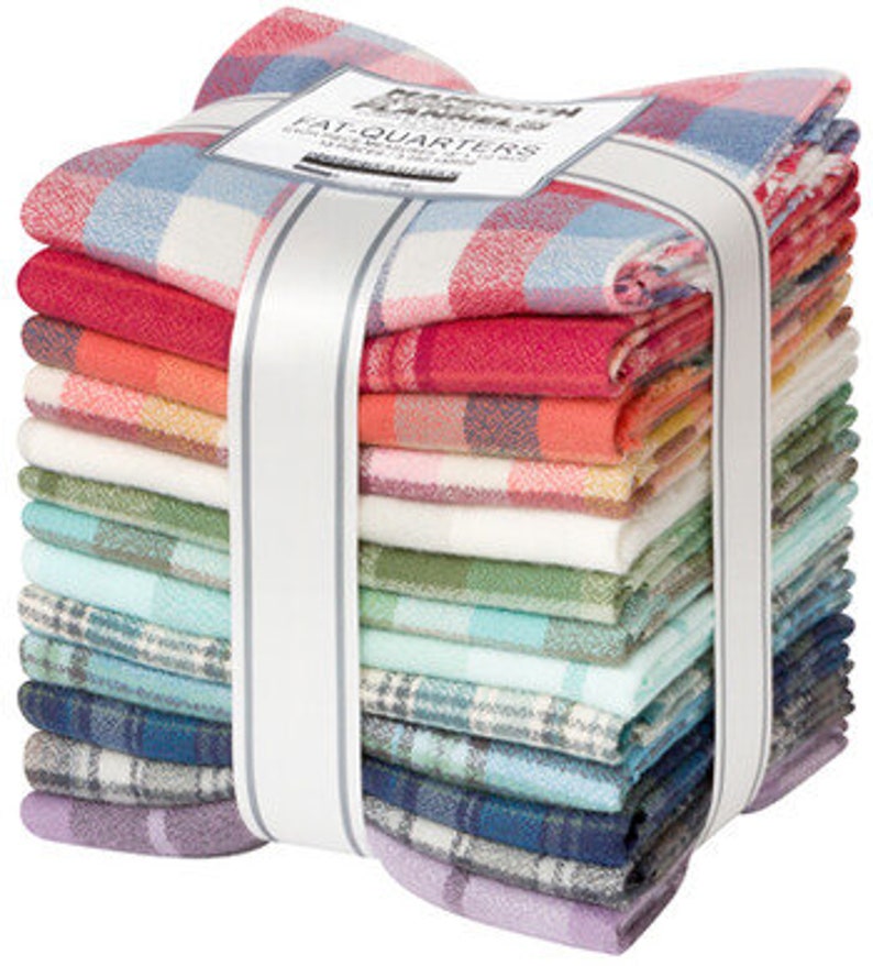 May include: A stack of colorful plaid fabric squares, bundled with a white ribbon. The fabric features a variety of colors, including red, blue, green, and purple. A label on top reads "Mammoth Flannel Fat Quarters".