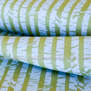 May include: A close-up of a fabric with a repeating pattern of green and blue stripes. The stripes are made up of a stylized tree bark design. The fabric is folded in half, showing the pattern on both sides.