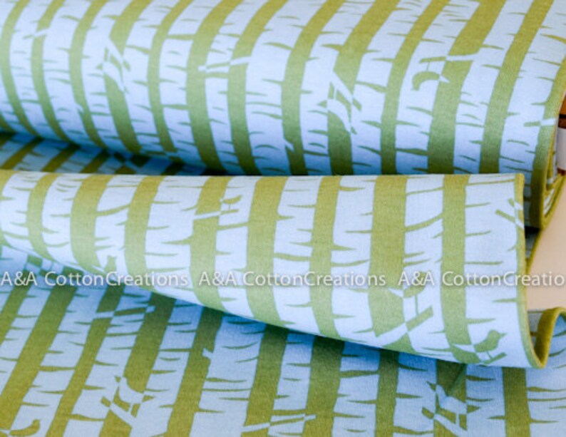 May include: A close-up of a fabric with a repeating pattern of green and blue stripes. The stripes are made up of a stylized tree bark design. The fabric is folded in half, showing the pattern on both sides.