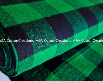 May include: Green and black plaid fabric with a woven texture. The fabric is folded in half and the edges are visible. A&A Cotton Creations is printed on the fabric.