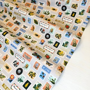 May include: A beige fabric with a repeating pattern of postage stamps featuring various insects, flowers, and plants. The stamps have a blue and white design with gold accents and the text "Par Avion" and "Please Deliver To".