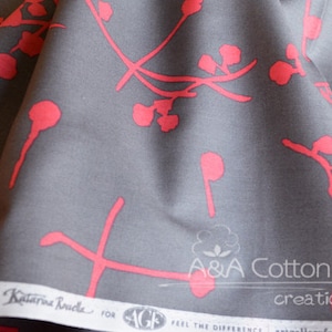 May include: Gray cotton fabric with a repeating pattern of pink stylized floral branches. The fabric has the text "A&A Cotton creations" printed on it.