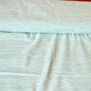 Puede incluir: Una tela azul claro con un patr&oacute;n ondulado blanco. La tela est&aacute; doblada por la mitad y el patr&oacute;n es visible en ambos lados.