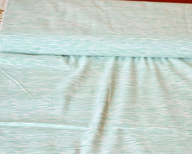 Puede incluir: Una tela azul claro con un patr&oacute;n ondulado blanco. La tela est&aacute; doblada por la mitad y el patr&oacute;n es visible en ambos lados.