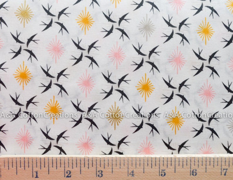 May include: White fabric with a repeating pattern of black birds, pink and yellow starbursts. The fabric is measured with a ruler in inches.