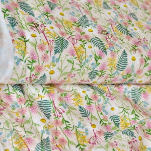 K&ouml;nnte beinhalten: Ein wei&szlig;er Stoff mit einem zarten Blumenmuster aus rosa, gelben und gr&uuml;nen Wildblumen und Farnen. Der Stoff hat einen dezenten rosa Hintergrund.