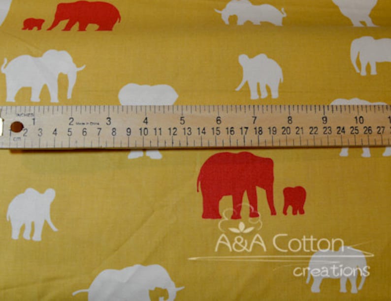 May include: A yellow fabric with a repeating pattern of white and red elephants. The elephants are in various sizes and positions. A ruler is placed on the fabric for scale. The text "A&A Cotton creations" is printed on the fabric.