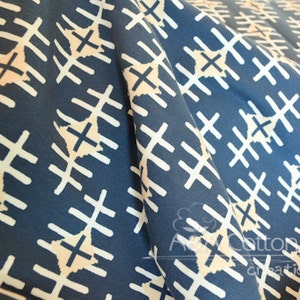 May include: A blue fabric with a white geometric pattern of crosses and lines. The fabric is folded in half, showing the pattern on both sides.