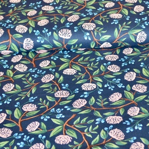 May include: A navy blue fabric with a repeating pattern of white flowers and green leaves. The fabric has a subtle texture and a soft, flowing feel.