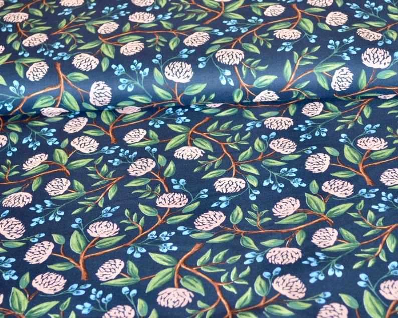 May include: A navy blue fabric with a repeating pattern of white flowers and green leaves. The fabric has a subtle texture and a soft, flowing feel.