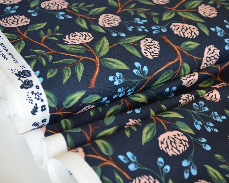May include: Navy blue fabric with a floral print featuring pink flowers, green leaves, and blue berries. The fabric is folded and has a white label with the text "Screen Printed in Japan".