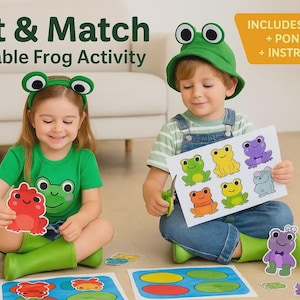 May include: Two children are seated on the floor, engaged in a frog-themed activity. The image features the text "Cut & Match Printable Frog Activity." One child holds a red frog cutout, while the other holds a sheet of colorful frog illustrations. The activity includes pond mats and instructions.