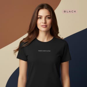 May include: A black crew neck t-shirt with the text "INNER OVER OUTER" in white. The word "BLACK" is displayed in a pink rectangle in the upper right corner. The background has a color block design with brown, beige, and navy blue.