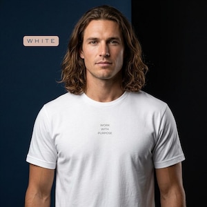 Può includere: T-shirt bianca girocollo con la scritta "WORK WITH PURPOSE" in nero. La parola "WHITE" è visualizzata in un riquadro rettangolare. La t-shirt è realizzata in un materiale morbido.