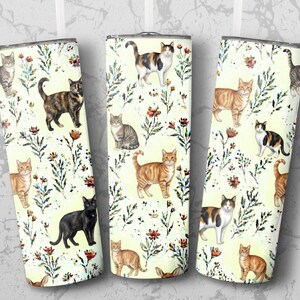 Pode incluir: Três canecas de aço inoxidável com um design de gato. As canecas apresentam ilustrações de gatos em várias cores e padrões, em um fundo amarelo claro com detalhes florais. Os gatos são retratados em várias poses.